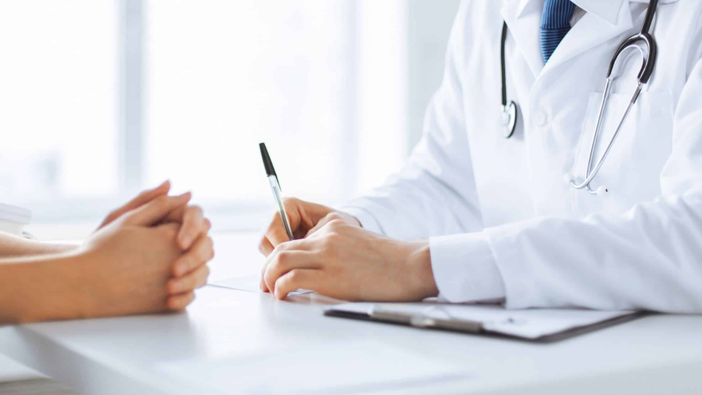 A doctor talking with a patient over a desk.