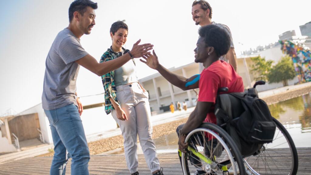 A man in a wheelchair greeting his friends.