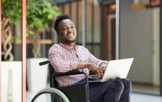 A man in a wheelchair working on a laptop.