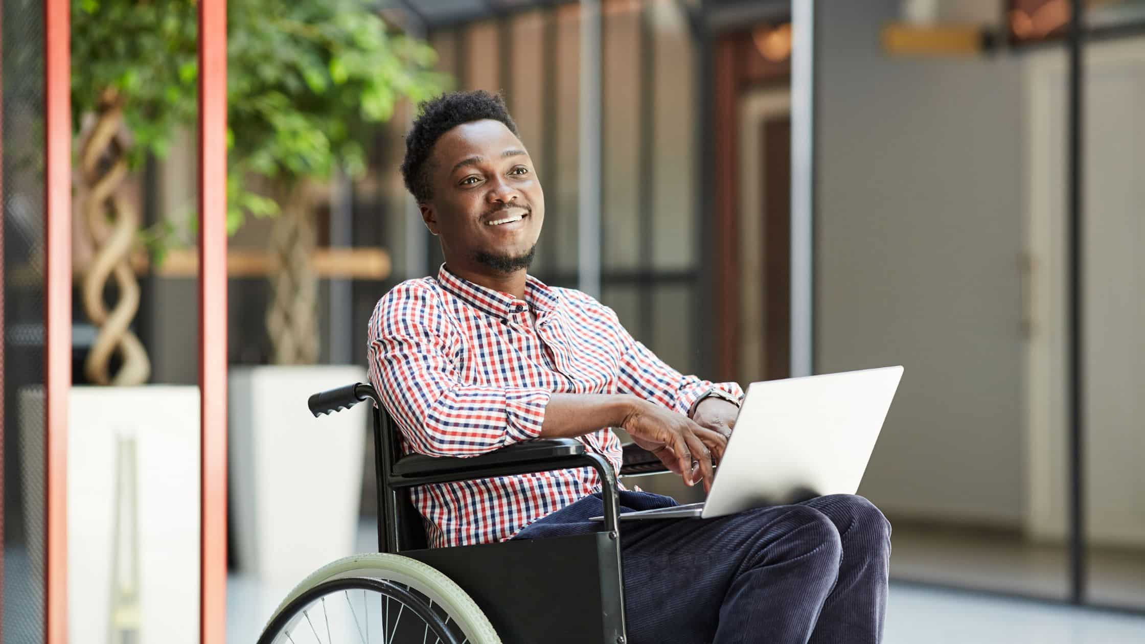 A man in a wheelchair working on a laptop.