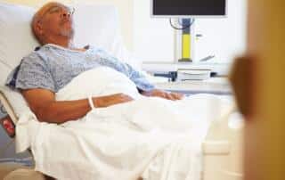 An elderly African-American man receiving medical care in the hospital.