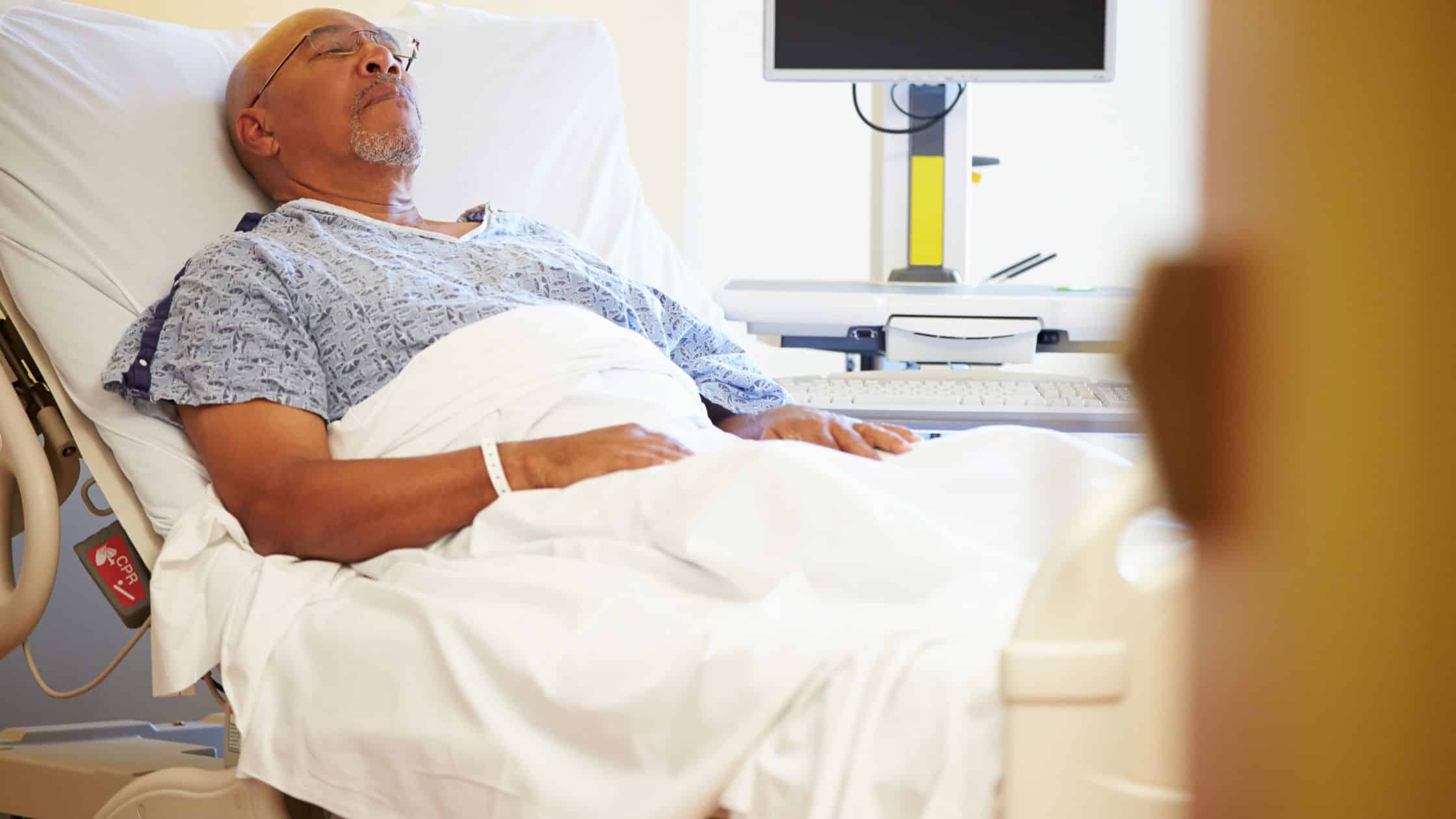 An elderly African-American man receiving medical care in the hospital.