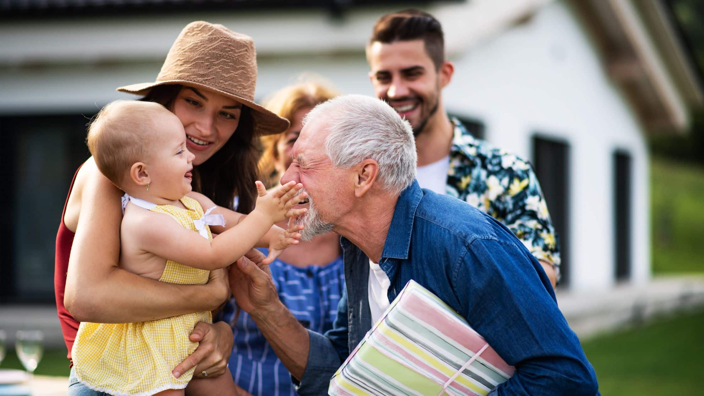 A multi-generational family celebrating in front of a house.