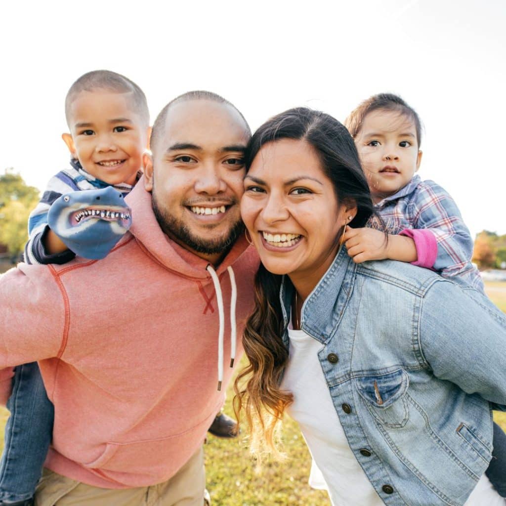 A mother and father with their two children, posing for a picture.
