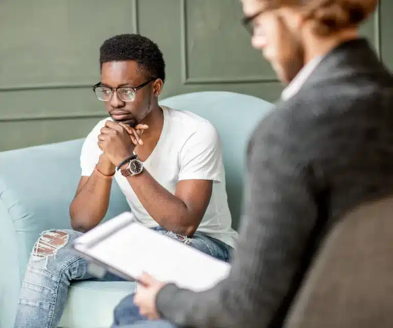 A man sitting on a couch, talking with his therapist.