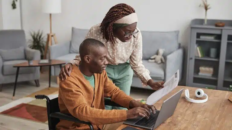 A man in a wheelchair and a woman going over papers.