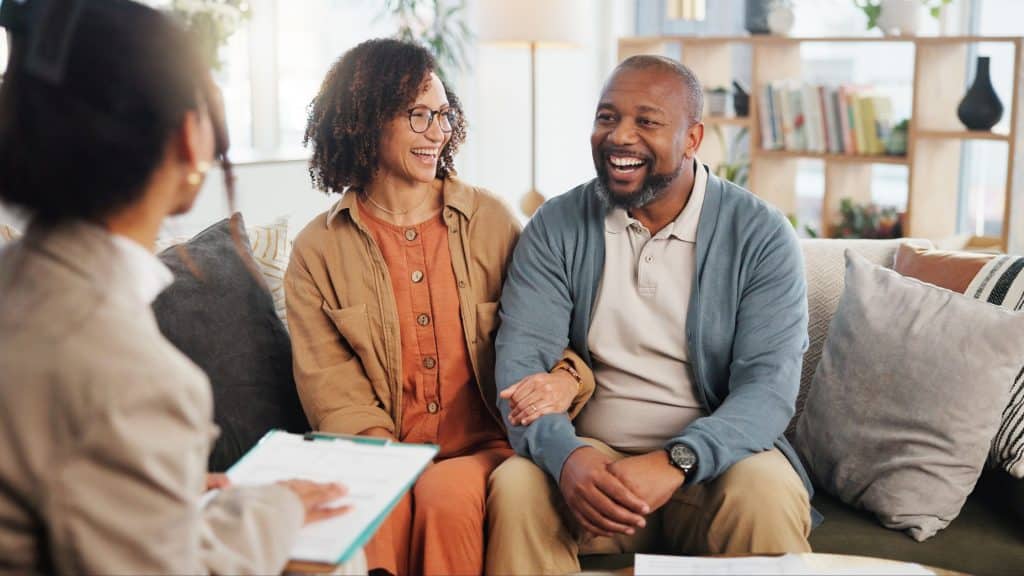 middle aged couple talking with their attorney and smiling.